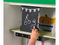 Kinderhand die met krijt op een schoolbord tekent in een speelgoedkeuken.