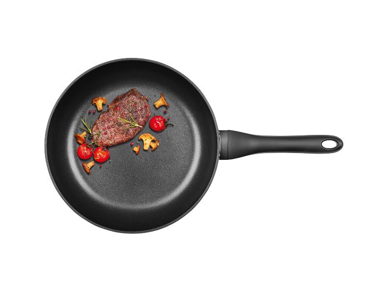 Een gebakken biefstuk met champignons en cherrytomaatjes in een pan.