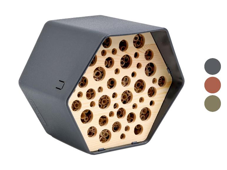 Zeshoekig insectenhotel met houten interieur en gaten van verschillende groottes, in donkergrijs.