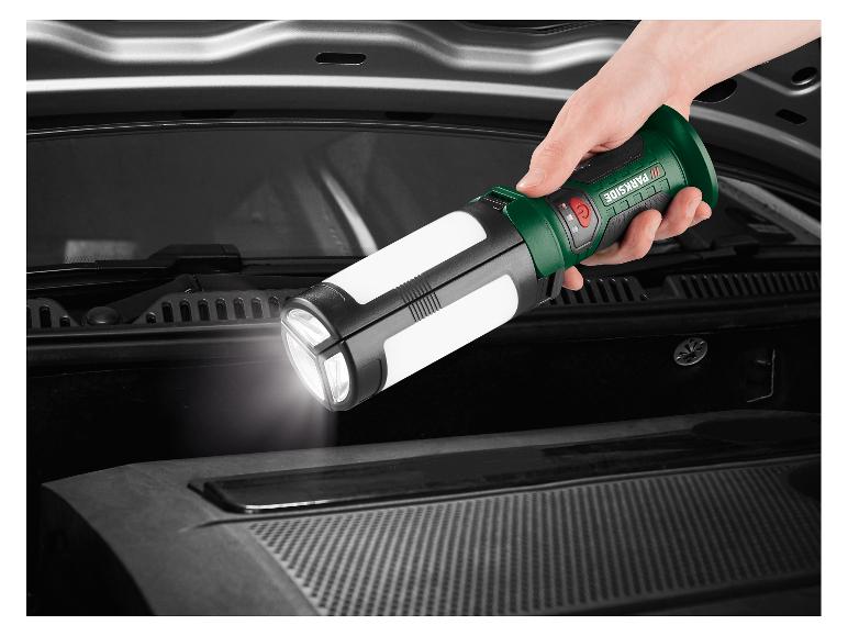 Een hand houdt een opvouwbare zaklamp vast die de motorruimte van een auto verlicht.