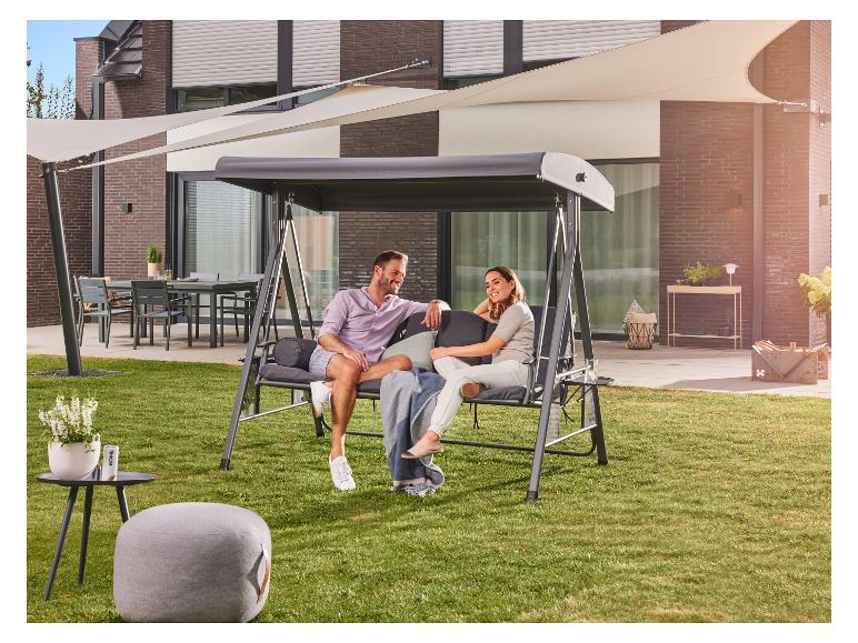 Een stel ontspant op een grijze tuinschommel met overkapping in een achtertuin met gazon.