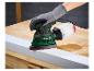 Hand met handschoen schuurt een witte plank met een Parkside schuurmachine op een houten tafel.