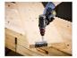 Persoon met handschoen schroeft scharnier in hout met accuboormachine.