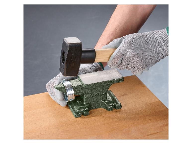 Persoon gebruikt een hamer en aambeeld om aan een metalen klem te werken.