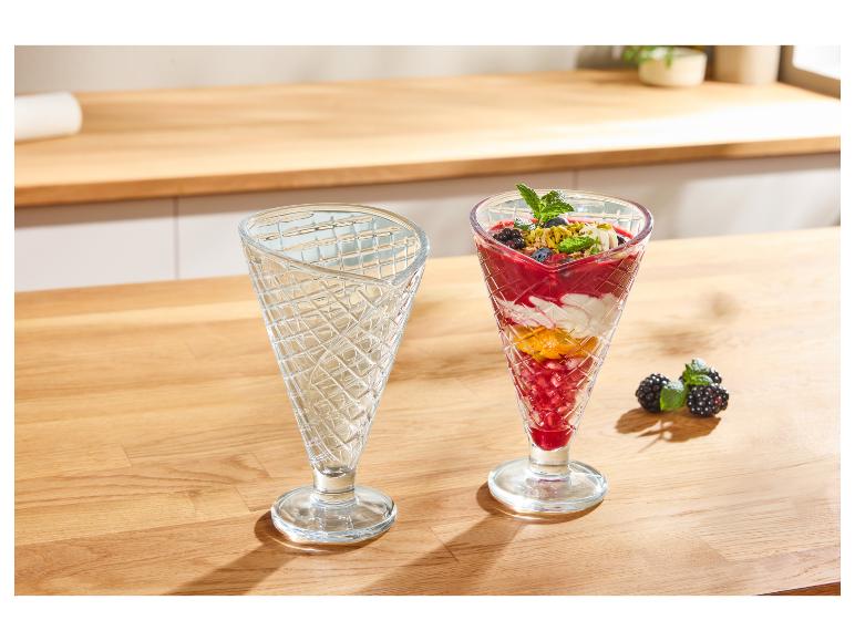 Twee glazen dessertglazen, één leeg en één gevuld met bessenparfait.