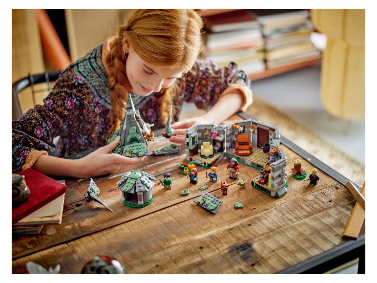 Een meisje speelt met LEGO Harry Potter sets op een houten tafel.