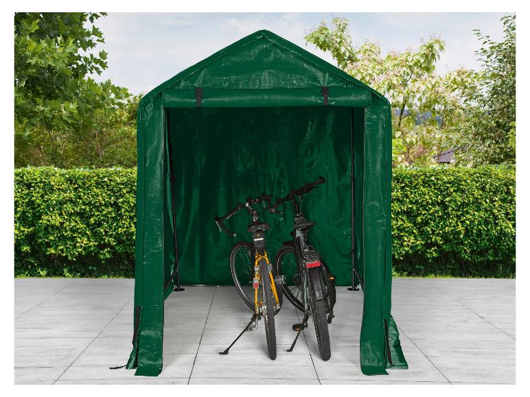 Groene fietsenstalling met twee fietsen erin geparkeerd, op een betegeld terras.