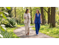 Twee vrouwen in stijlvolle pakken wandelen en praten in een groen park.