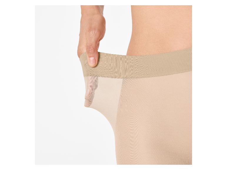 Hand rekt huidkleurige panty uit, toont elasticiteit.