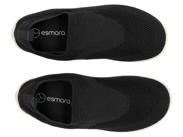 Paar zwarte gebreide instappers met witte zolen, van bovenaf gezien.