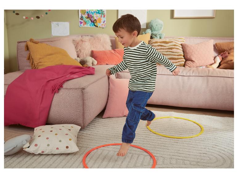 Een klein kind speelt met hoepels op een zacht tapijt.