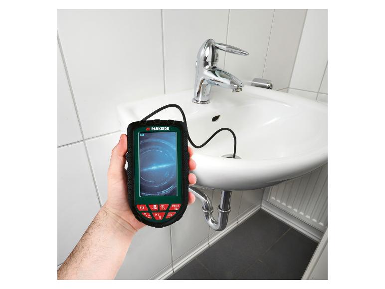 Een man houdt een Parkside inspectiecamera voor leidingen vast, terwijl hij een afvoer van een wastafel inspecteert.