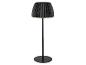 Zwarte vloerlamp met geplooide kap, die een warme gloed afgeeft.