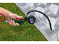Hand houdt een opblaaspistool met drukmeter vast, waarmee een transparant luchtbed op gras wordt opgeblazen.