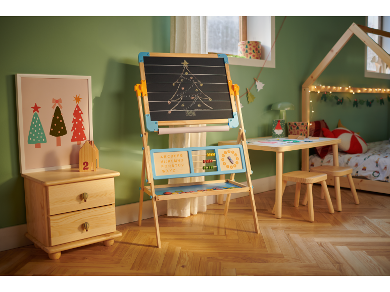 Kinderkamer met houten ezel, kleine tafel met krukjes en bed, versierd voor Kerstmis.