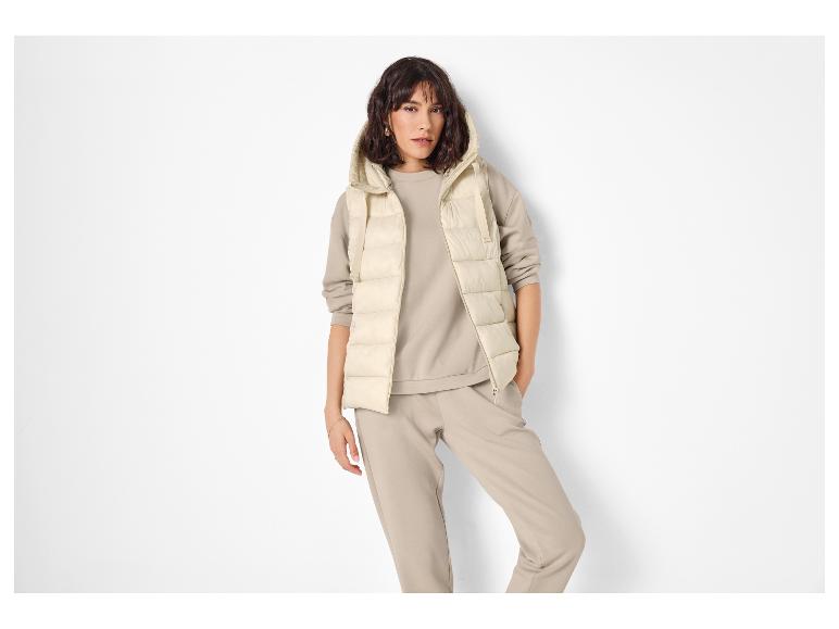Vrouw in beige gewatteerd vest en bijpassend trainingspak.
