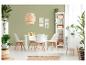 Eetkamer met witte tafel, stoelen, rek en planten in rieten manden.
