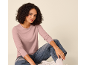 Vrouw in een roze shirt met lange mouwen en blauwe jeans, zittend op de grond.