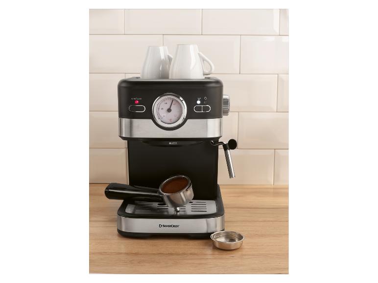 Espressomachine met twee kopjes en portafilter met koffie op een houten aanrecht.