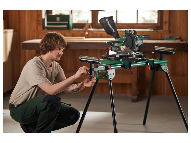 Een man zet een Parkside kap- en verstekzaag op een onderstel.