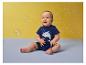 Lachende baby in blauwe haaienromper, omringd door bellen.