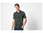 Man in een groen poloshirt met tropische print en jeans.