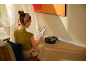 Vrouw bedient robotstofzuiger met smartphone in de woonkamer.