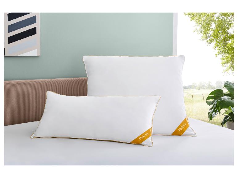 Twee witte Palette Gold Edition kussens op een bed met een bruin hoofdbord