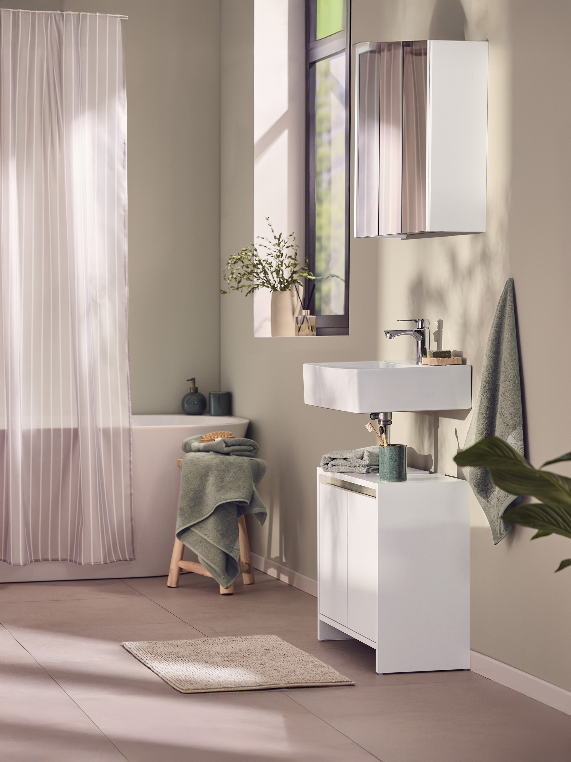Moderne badkamer met witte wastafel, wastafelmeubel en gestreept douchegordijn.
