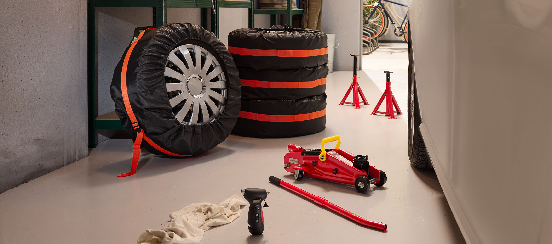 Autobanden met hoezen, krik en assteunen in een garage.