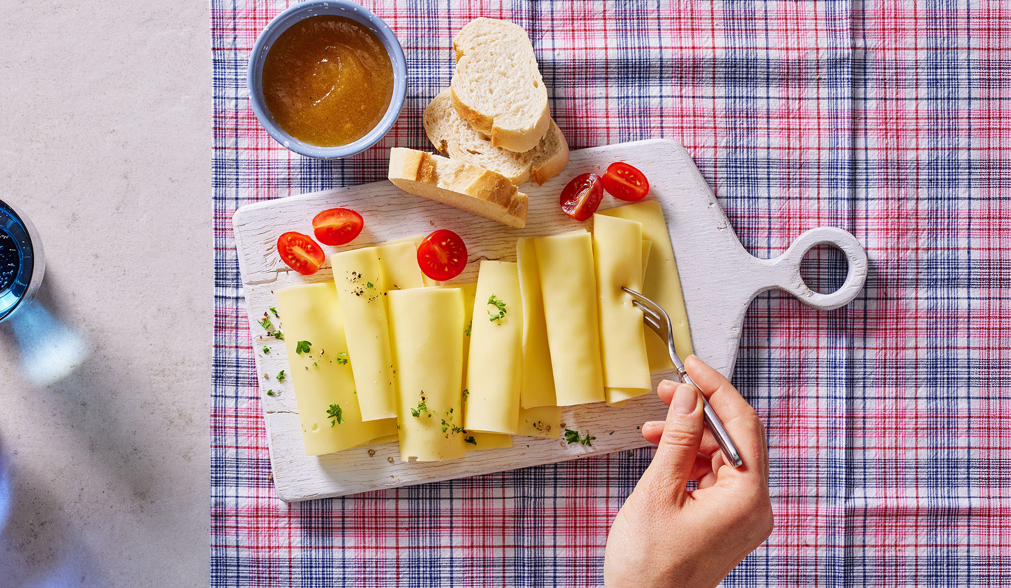Kaasplakken, cherrytomaten, brood en jam op een serveerplank.