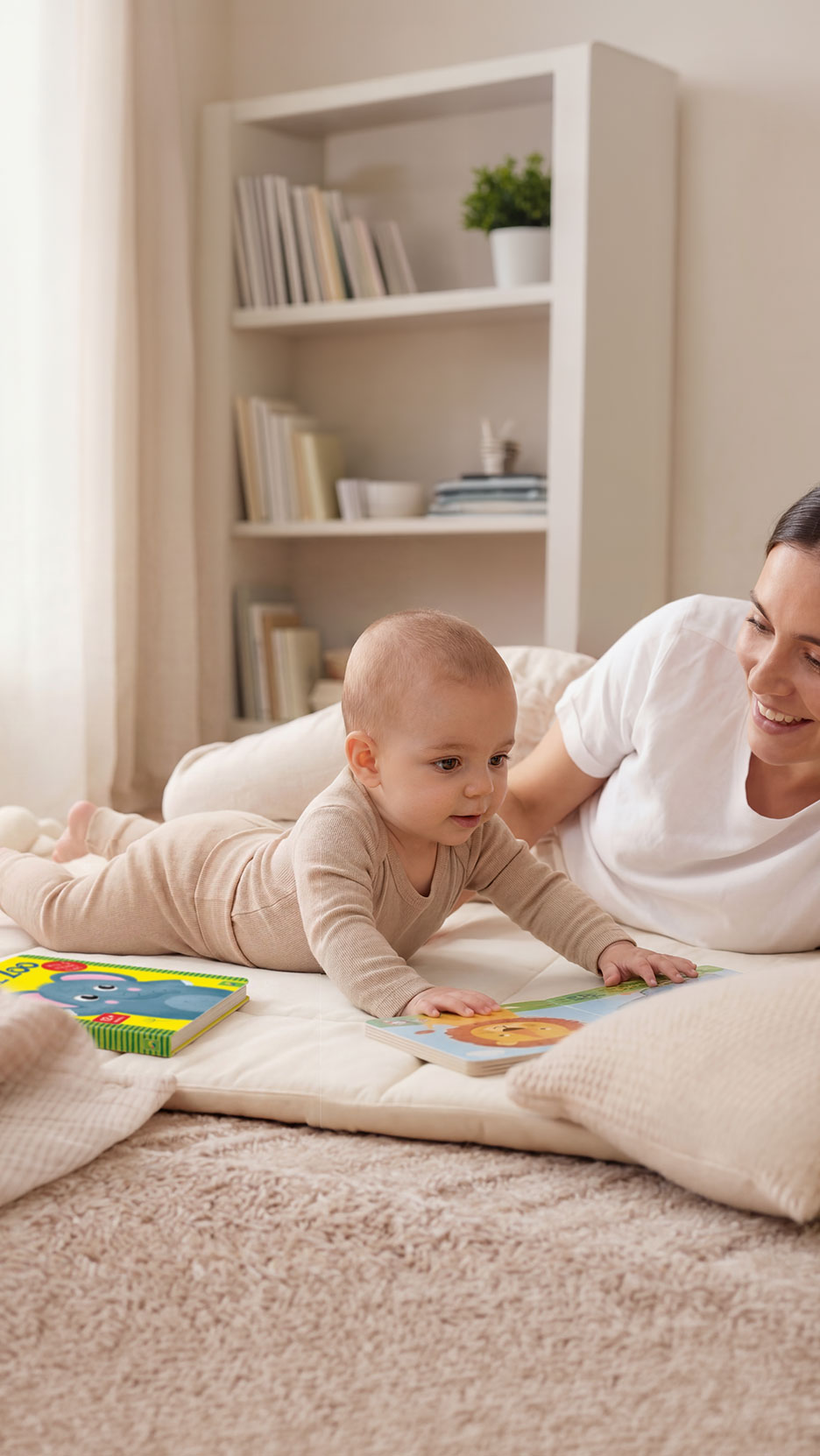 Baby en moeder op mat met boeken, naast een boekenplank.
