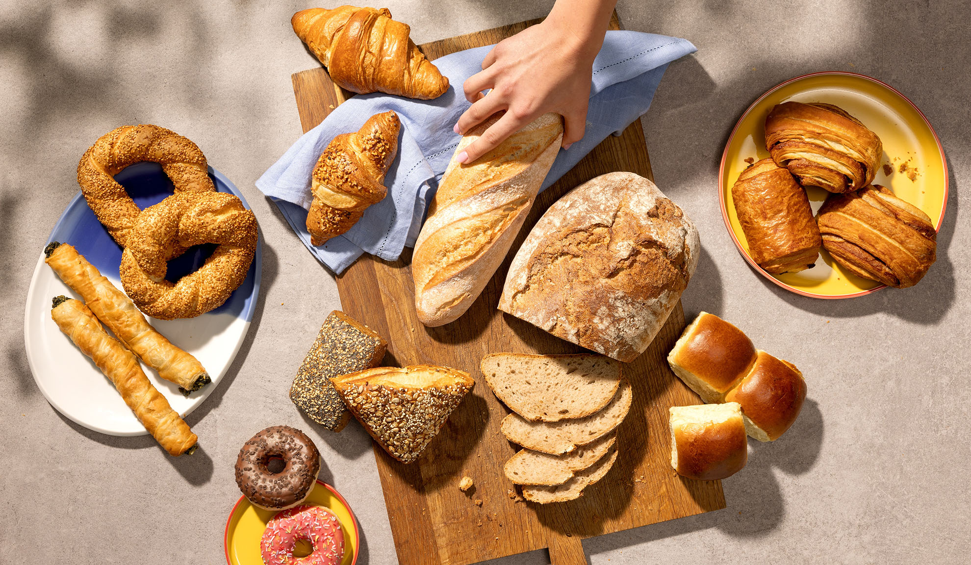 Assortiment van vers gebakken producten, waaronder brood, croissants, gebak en donuts op een tafel.