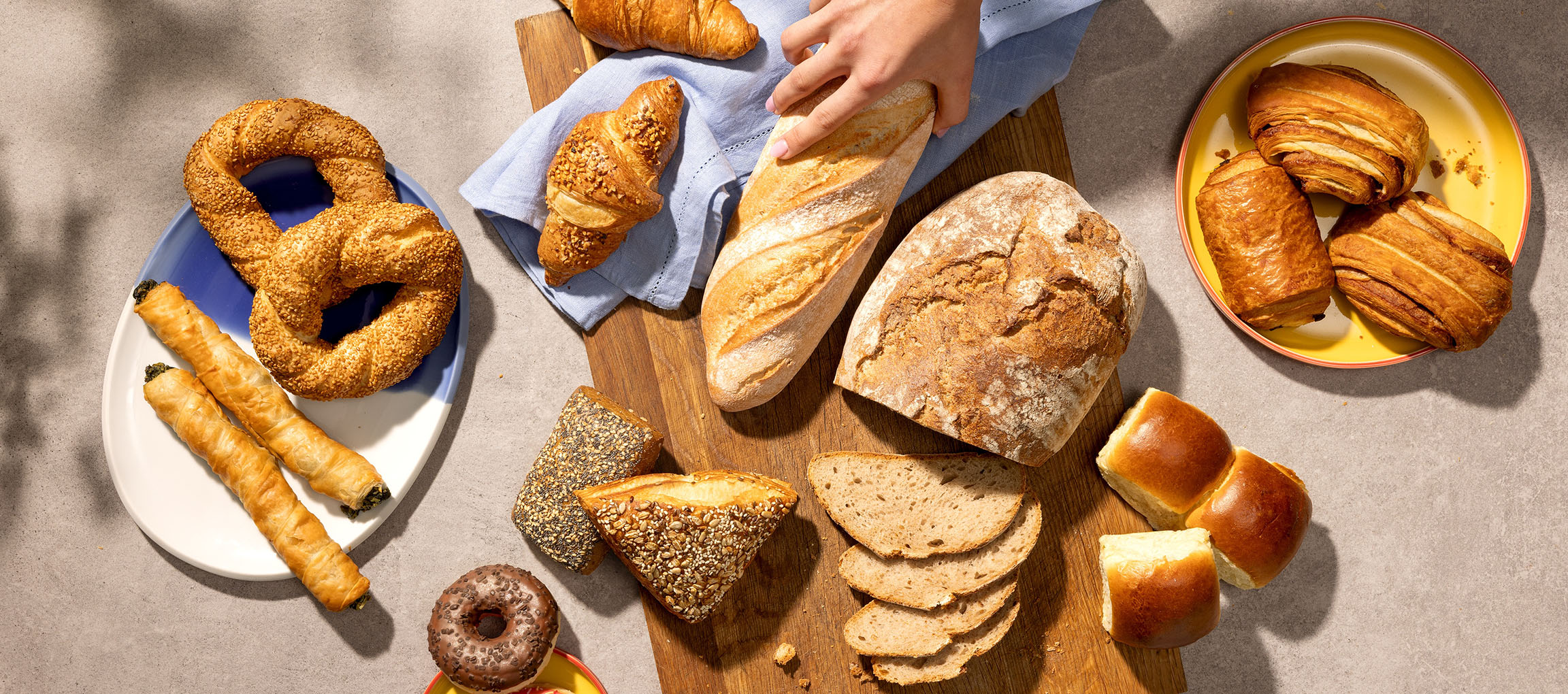 Assortiment van gebak en brood, waaronder pretzels, croissants en baguettes, op een tafel.