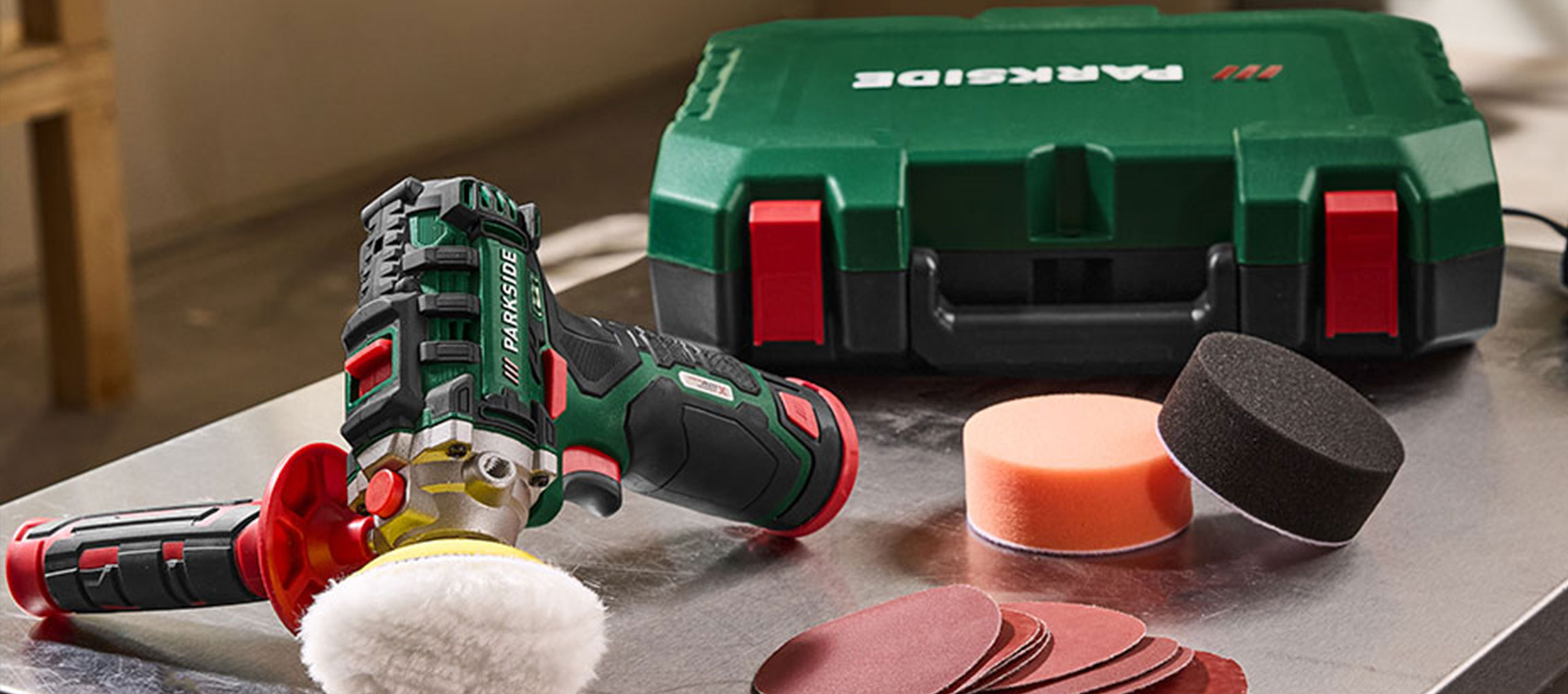 Polijstmachine met accessoires en groene gereedschapskist op een metalen oppervlak.