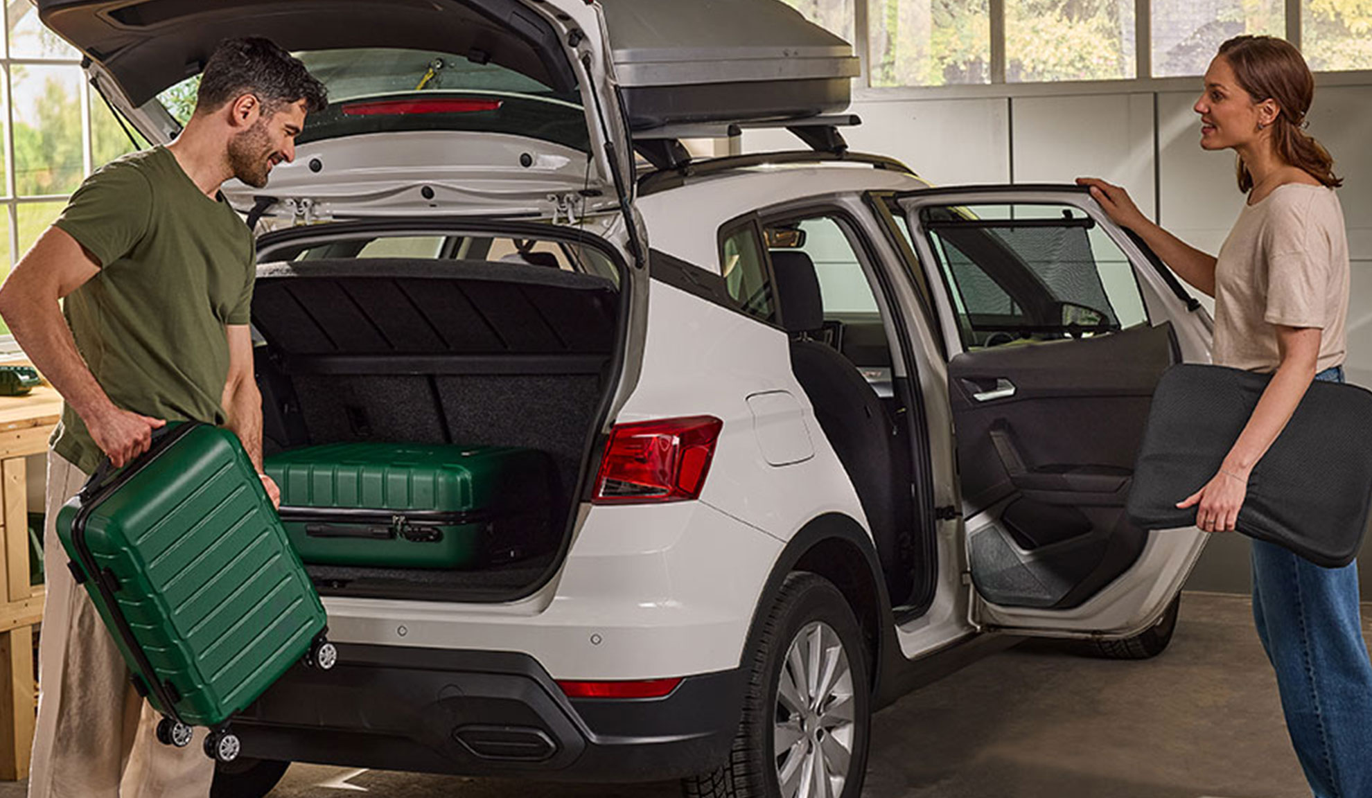 Koppel pakt bagage en autoaccessoires in een witte SUV voor een reis.