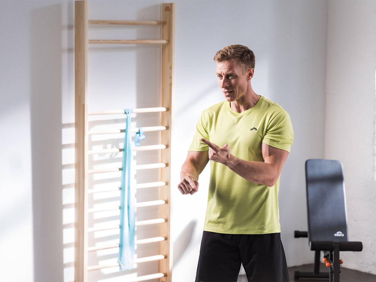 Een man in sportkleding staat voor een rekstok met een weerstandsband.