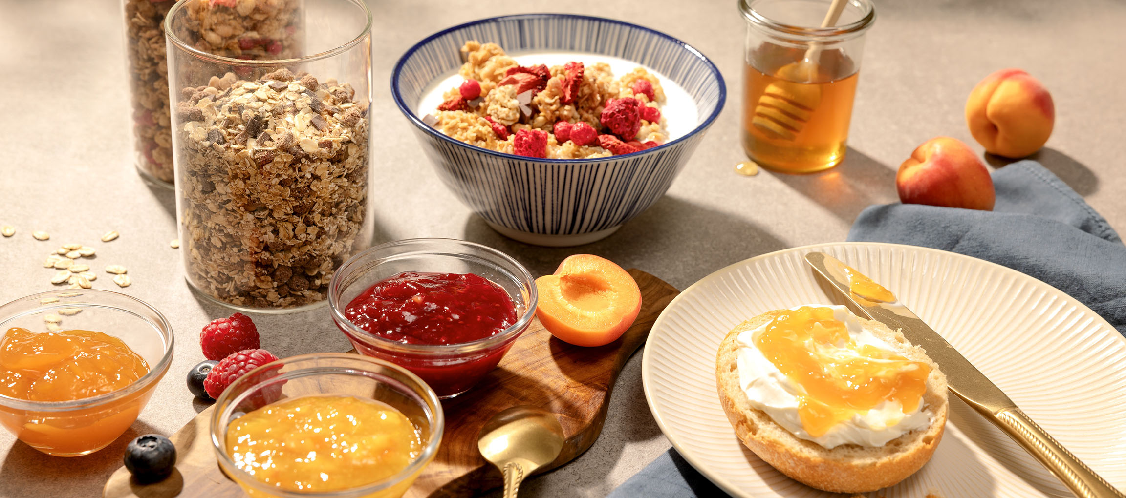 Ontbijt met muesli, jam, honing en brood met roomkaas en jam.