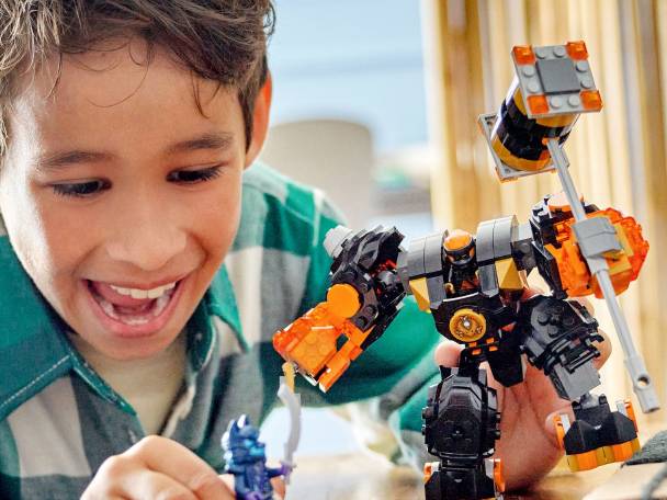 Lachende jongen speelt met een LEGO-robot en een klein LEGO-figuur.
