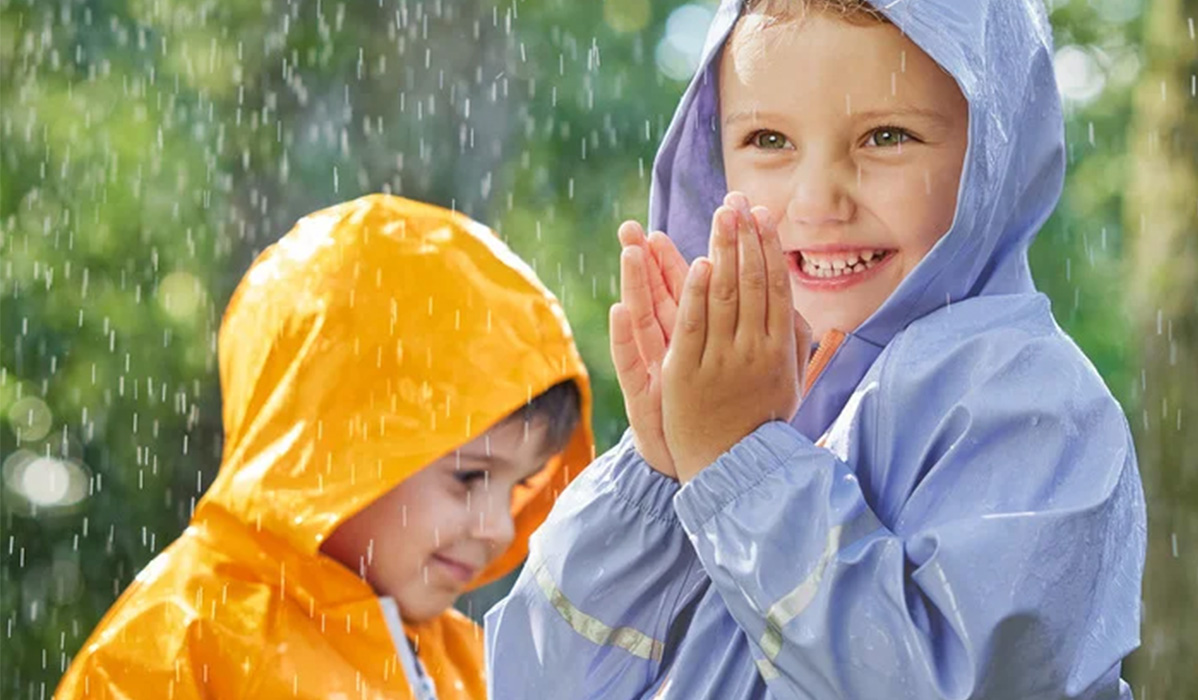 Kinderen in gele en blauwe regenjassen spelen in de regen.