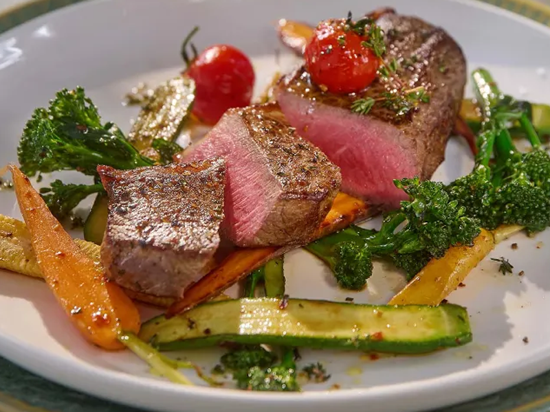 Biefstuk met geroosterde broccoli, wortels en courgette, gegarneerd met cherrytomaatjes en tijm.