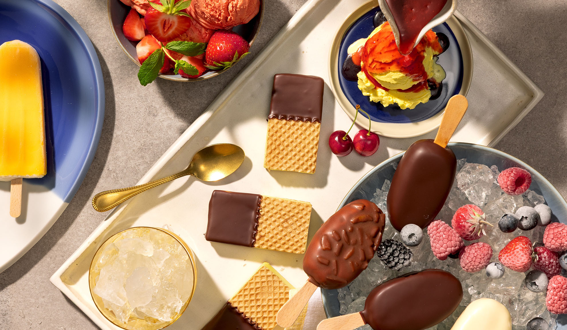 Assortiment van ijsrepen, waterijsjes, wafels en bessen op een dienblad.