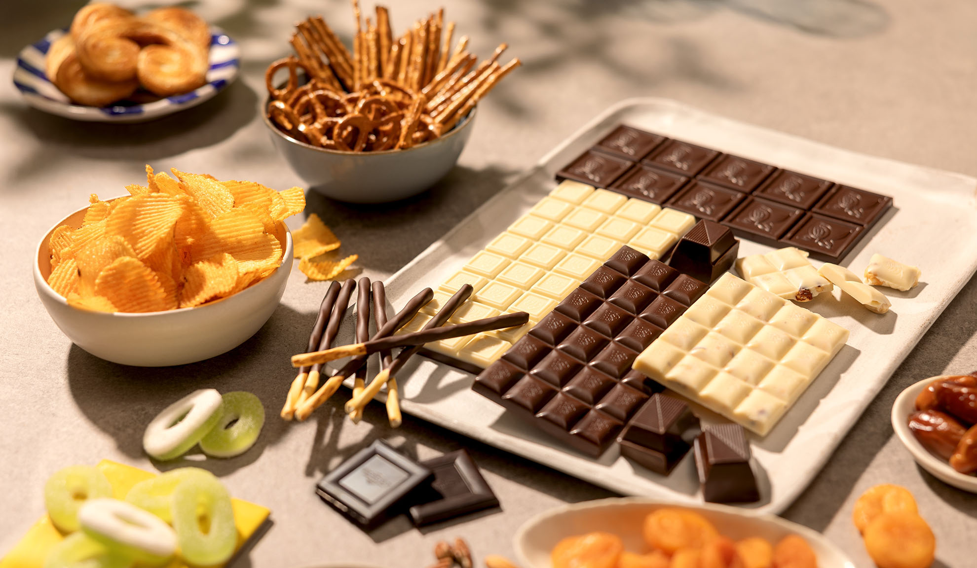 Een assortiment snacks waaronder chocoladerepen, chips, pretzels en snoep.