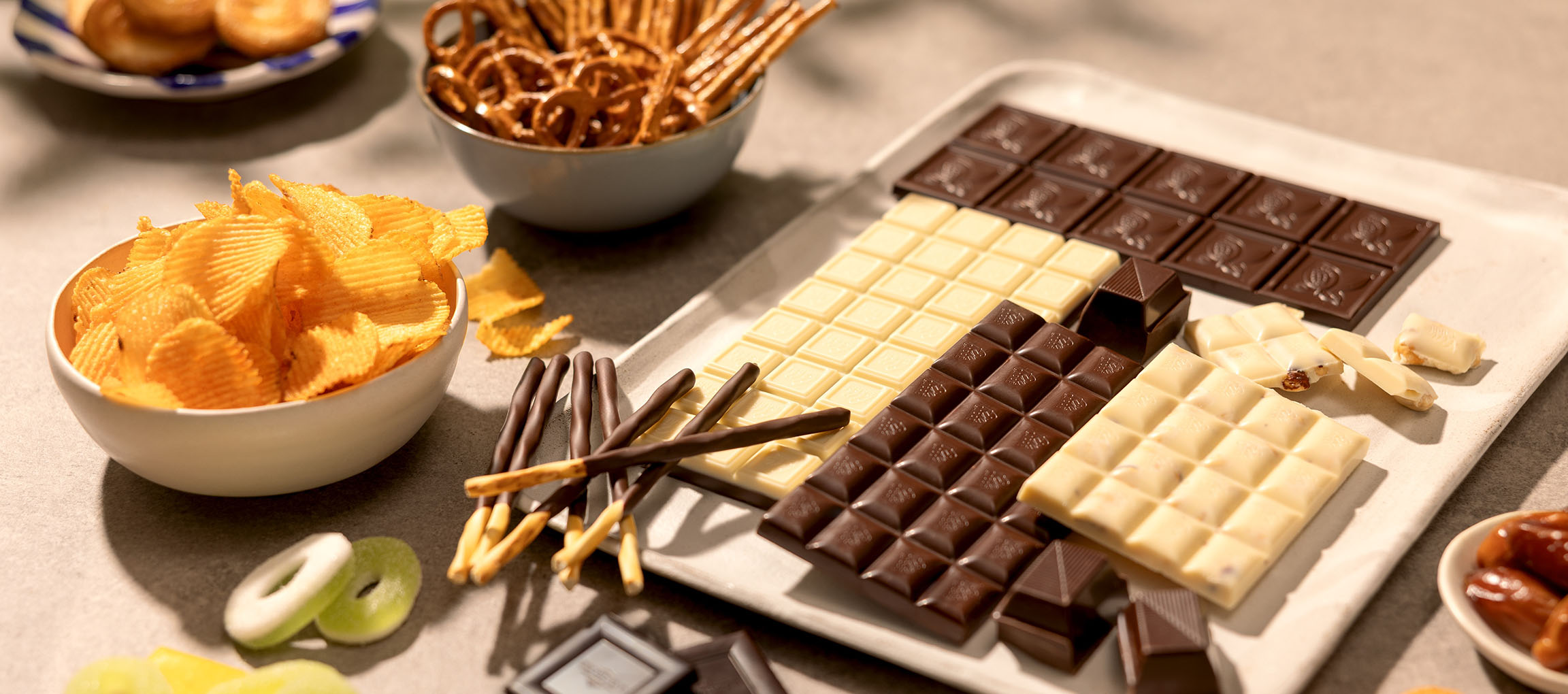 Diverse chocola, chips, pretzels en snoep op een tafel.