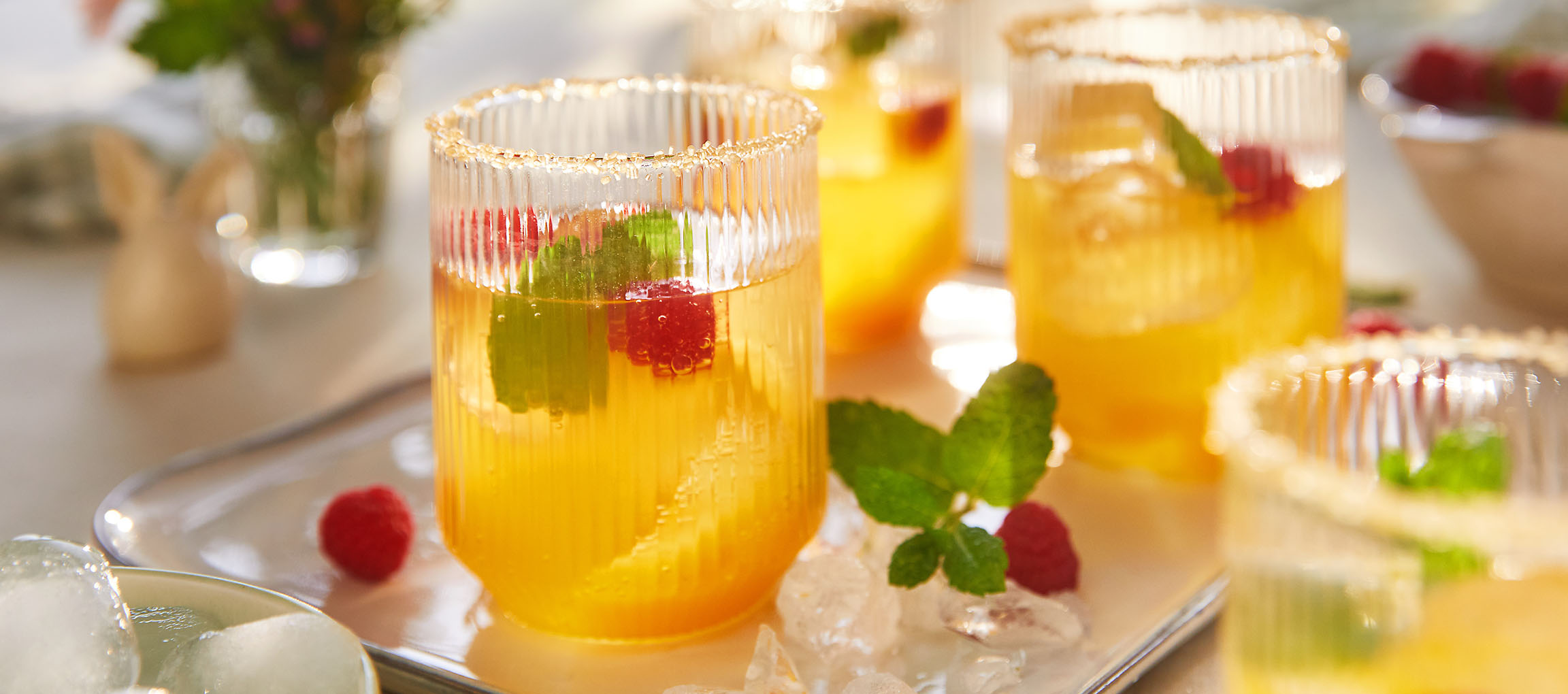 Glazen verfrissende drank met frambozen en munt, geserveerd op een dienblad.