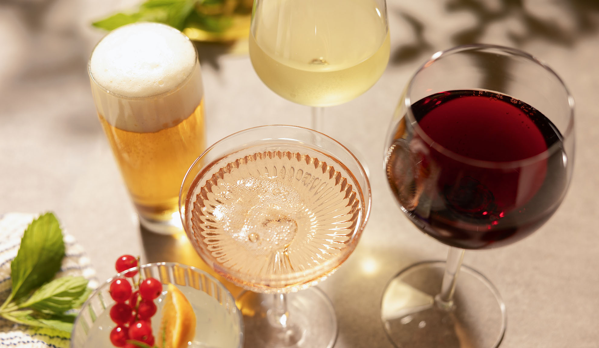 Glazen bier, witte, rosé en rode wijn, met een cocktail en bessen.