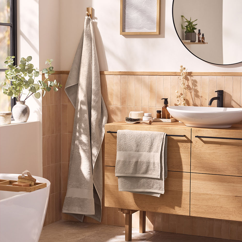 Moderne badkamer met beige handdoeken, witte wastafel en houten meubels.