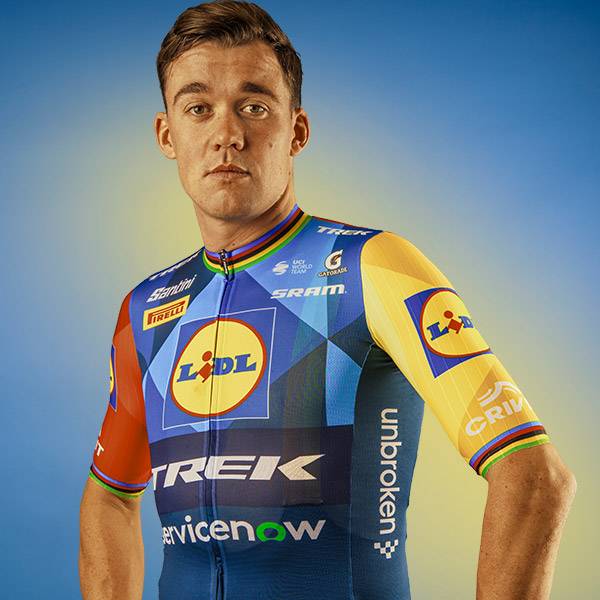 Man in een blauw en geel fietsshirt met een supermarktlogo en de tekst 'unbroken'.