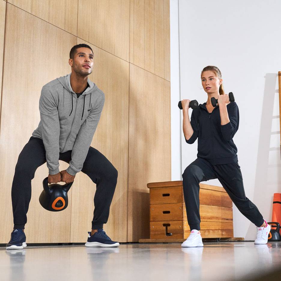 Man en vrouw in sportkleding, trainen met een kettlebell en dumbbells.