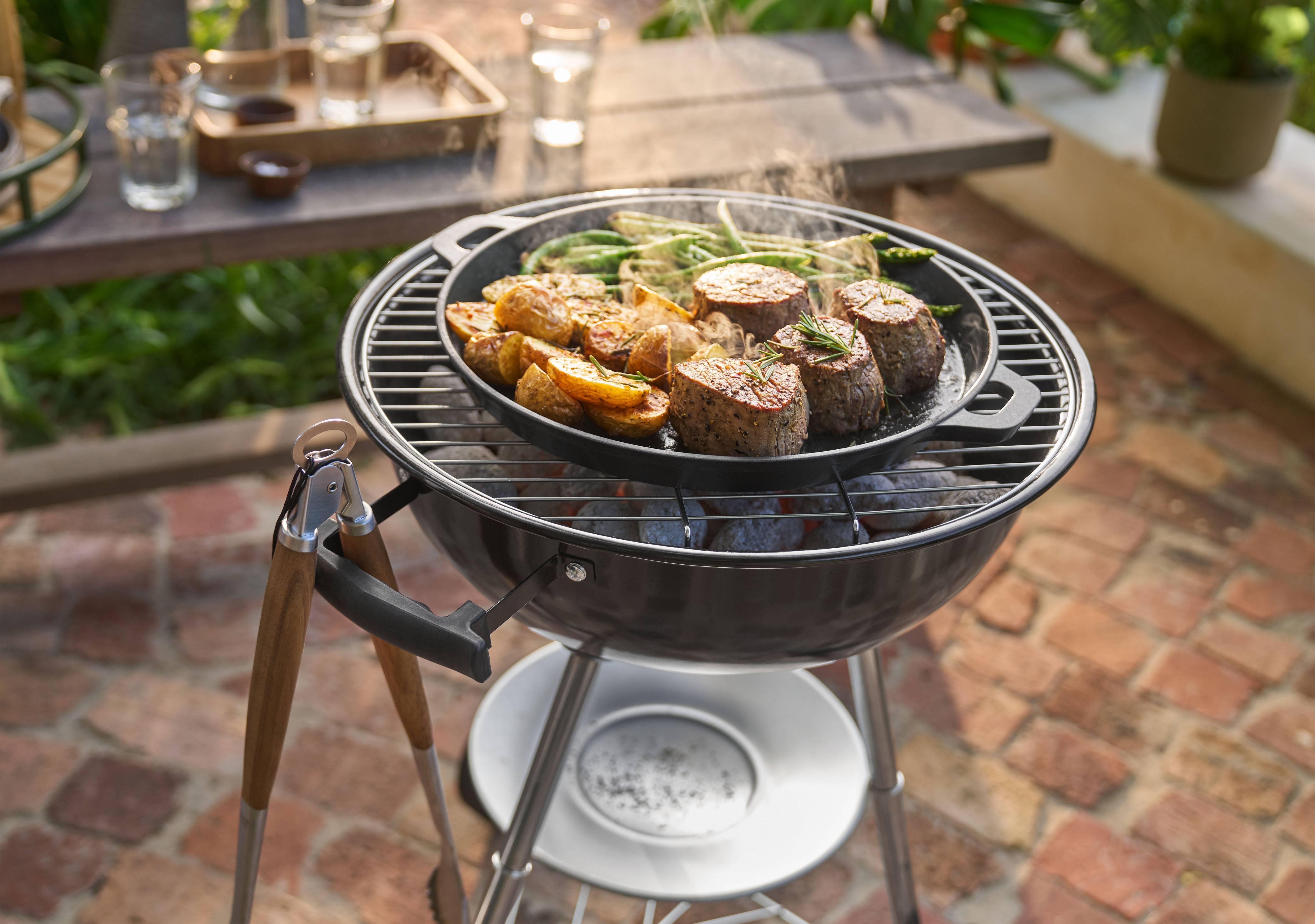 Barbecue met vlees, aardappelen en sperziebonen die buiten in een pan koken.